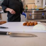 Chef Phillip Dell Cuts Andouille Sausage for Mardi Gras Themed Grilling Class