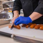 Chef Phillip Dell Cuts Andouille Sausage for Mardi Gras Themed Grilling Class