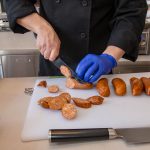 Chef Phillip Dell Cuts Andouille Sausage for Mardi Gras Themed Grilling Class